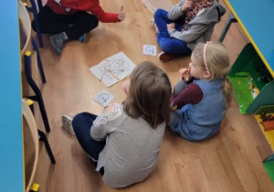Dzieci siedzą dookoła ułożonego z części obrazka przedstawiającego bociana
